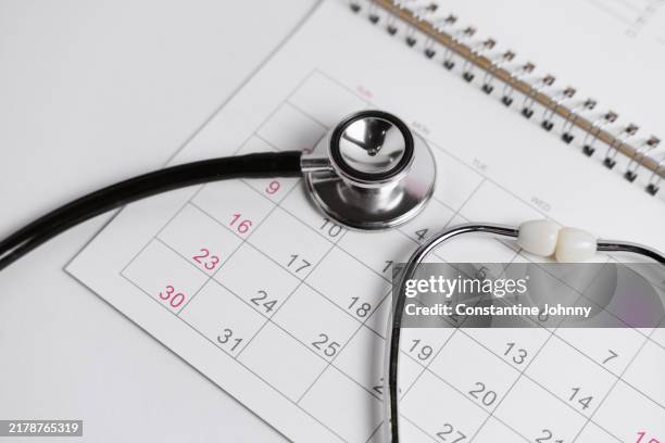 stethoscope on calendar. healthcare scheduling concept. - frist stock-fotos und bilder