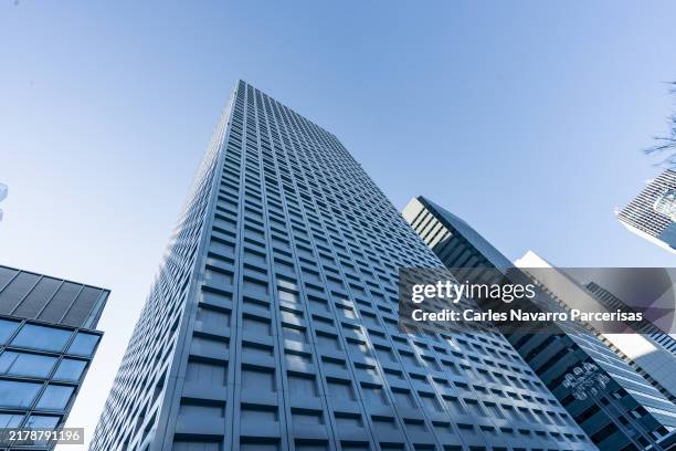 modern skyscraper towering over a city skyline with clear blue skies - financial building stock pictures, royalty-free photos & images