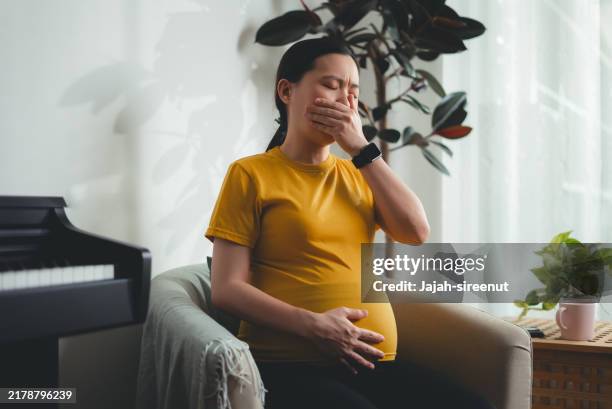 asian pregnant woman was sick with morning sickness sitting in living room at home. - pregnancy nausea stock pictures, royalty-free photos & images