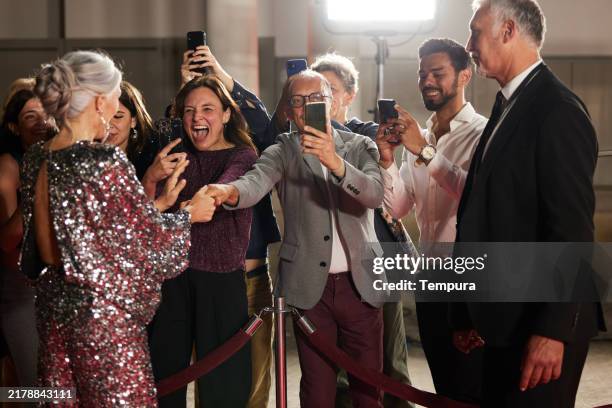 fans cheer loudly at the red carpet event as they eagerly ask the actors for autographs. - red carpet paparazzi stock pictures, royalty-free photos & images