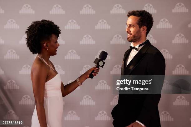 before the step-and-repeat wall, a movie star stops on the red carpet, ready to speak with a reporter. - fotografia promocional imagens e fotografias de stock