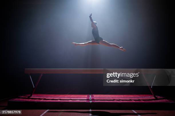 donna ginnasta che si esibisce alla trave di equilibrio - gambe divaricate foto e immagini stock