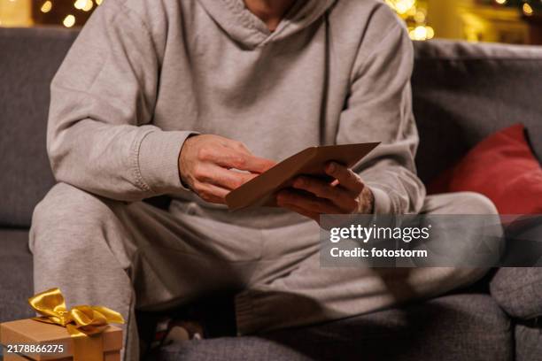unrecognizable man opening christmas greeting card - man reading card stock pictures, royalty-free photos & images