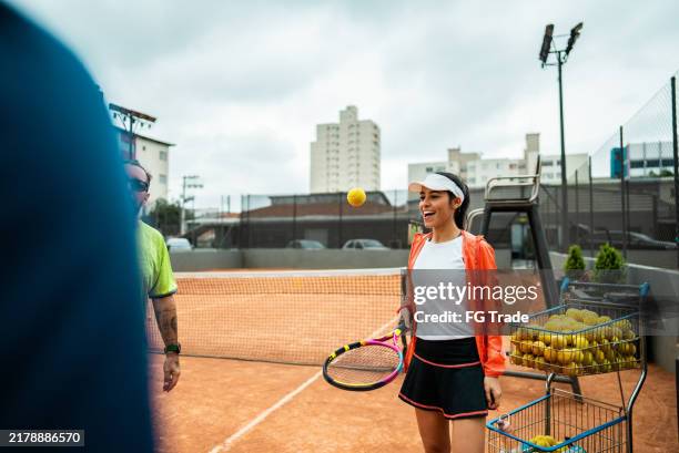joueur de tennis discutant avec des amis sur un court de tennis - balle de tennis photos et images de collection