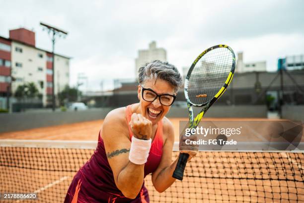 portrait of a tennis player celebrating on a tennis court - vuist stockfoto's en -beelden