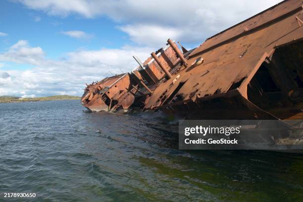 a shipwreck listing to port side in shallow water - labrador photos et images de collection