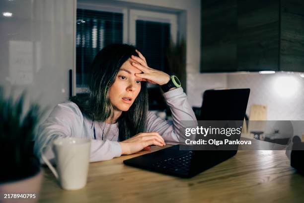 tired and upset midl-aged woman works in a home office at night - fraud stock pictures, royalty-free photos & images