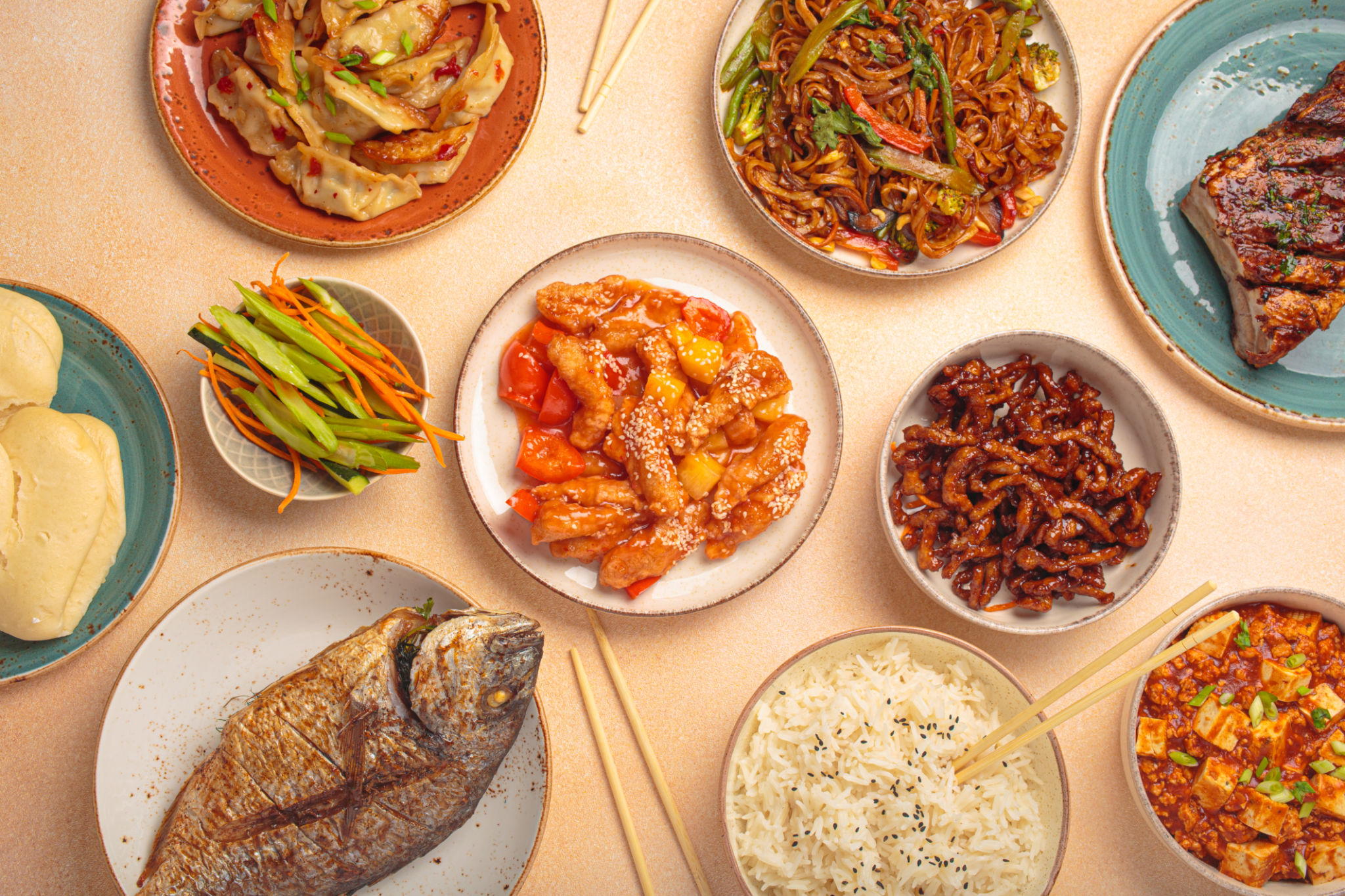Assorted traditional chinese dishes top view on a table: kung pal chicken, sweet and sour pork, noodles, dumplings, mapo tofu, fish, rice Assorted traditional chinese dishes top view on a table: kung pal chicken, sweet and sour pork, noodles, dumplings, mapo tofu, fish, rice