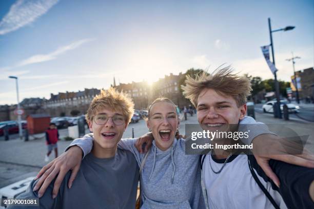 glückliche teenager sprechen über selfies in der stadt saint-malo, bretagne, frankreich. - jugendalter stock-fotos und bilder