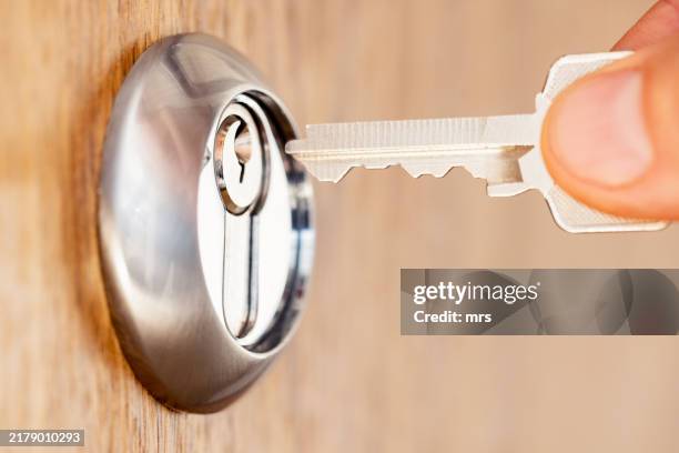 hand putting key in door lock - abrir con llave fotografías e imágenes de stock