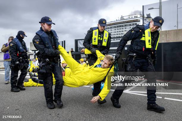 Dutch Police officers remove a demonstrator as activists of environmental movement "Extinction Rebellion" take part in an action around the arrival...