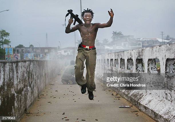 Liberian militia commander loyal to the government exults after firing a rocket-propelled grenade at rebel forces at a key strategic bridge July 20,...