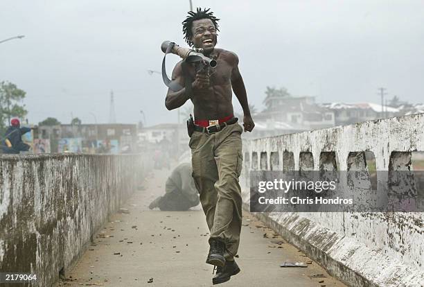 Joseph Duo, a Liberian militia commander loyal to the government, exults after firing a rocket-propelled grenade at rebel forces at a key strategic...