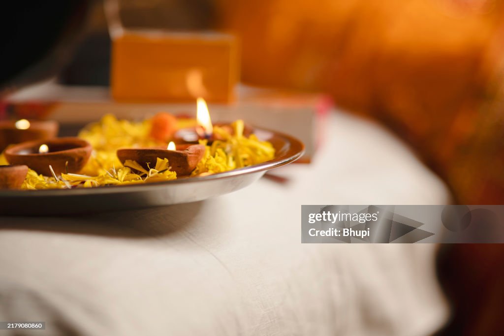 Close up of oil lamp (Diya) puja thali with flower and indian sweet on Diwali festival in India.