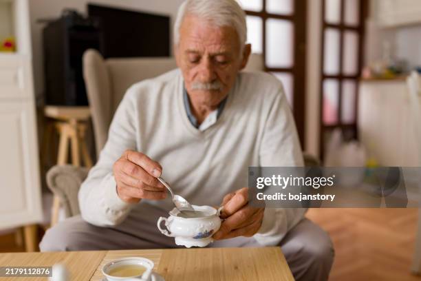 älterer mann genießt eine tasse tee zu hause - einzelner senior stock-fotos und bilder