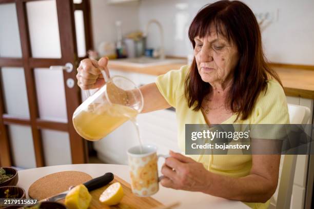senior woman preparing healthy morning tea - herbal tea stock pictures, royalty-free photos & images