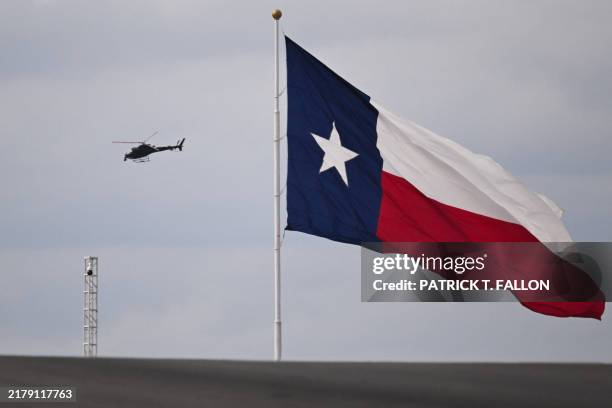Red Bull pilot Aaron Fitzgerald flies the an AStar AS350 helicopter past the Texas state flag while filming a practice session for the United States...