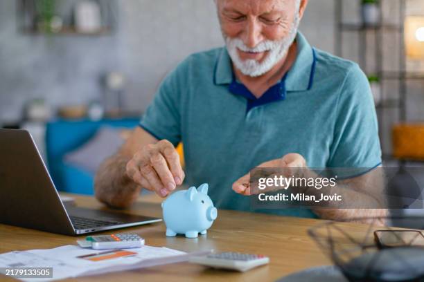 glücklicher und lächelnder senior hält sparschwein - spardose stock-fotos und bilder