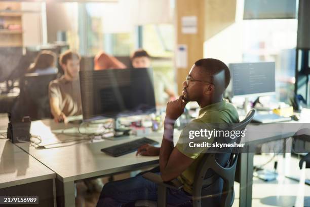 thoughtful black programmer working on pc in the office. - it professional stock pictures, royalty-free photos & images
