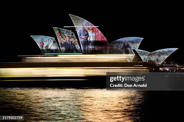 A ferry sails past as the Sydney Opera House shells are illuminated ...