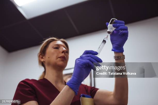 female nurse concentrating while preparing an injection in a medical center, close-up of hands and syringe. - acupuncture needle stock pictures, royalty-free photos & images