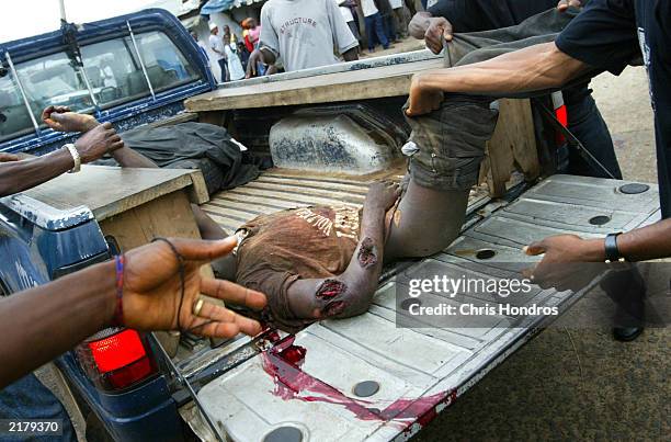 Liberian militiamen load the body of a rebel soldier outside a police station July 20, 2003 in Monrovia, Liberia. Government forces succeeded in...