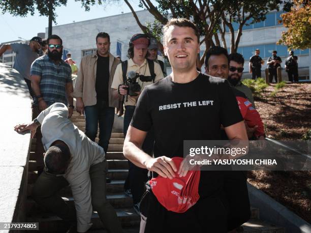 Conservative political activist and YouTuber Charlie Kirk holds a red cap supporting former US President and Republican presidential candidate Donald...