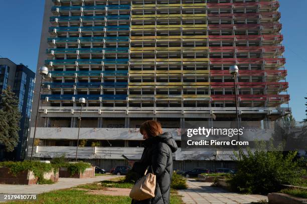 Woman checks her smartphone outside the ruins of the former Hotel National, whose facade is painted in the colors of the Moldovan flag on October 22,...