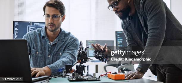black and white male software developer programmers work together on robot hand machine coding, use computer control robotic arm circuit. programming language, hardware development technology concept - inventor stock pictures, royalty-free photos & images