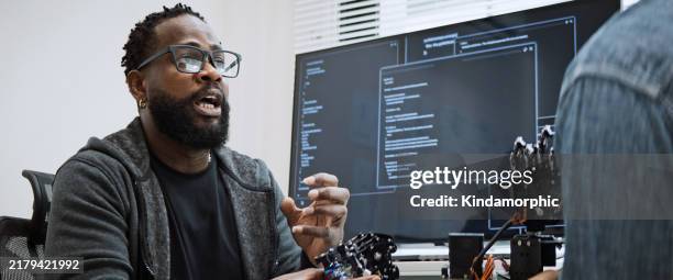 schwarze und weiße männliche softwareentwickler programmieren gemeinsam an der codierung von roboterhandmaschinen und verwenden die computersteuerung des roboterarmschaltkreises. programmiersprache, hardwareentwicklung, technologiekonzept - python-programmiersprache stock-fotos und bilder