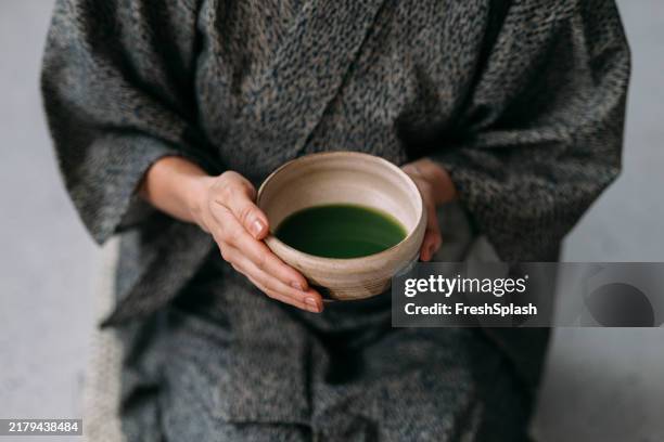 femme tenant un bol de thé matcha en tenue traditionnelle - cérémonie du thé photos et images de collection