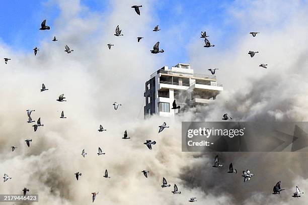 Flock of pigeons flies away as a smoke cloud erupts after a rocket fired by an Israeli war plane hit a building in Beirut's southern suburb of Shiyah...