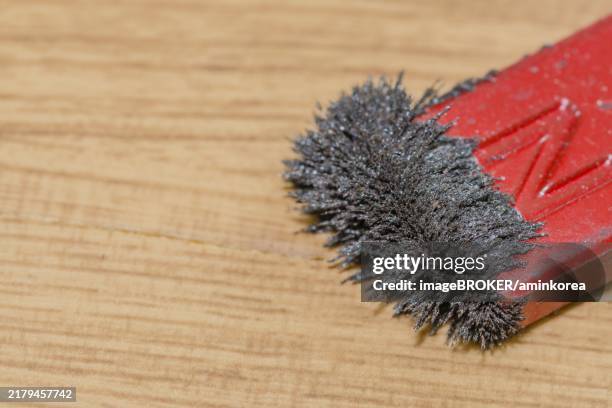 red magnet attracting iron filings, illustrating a magnetic field in a scientific context - iron filings stock pictures, royalty-free photos & images