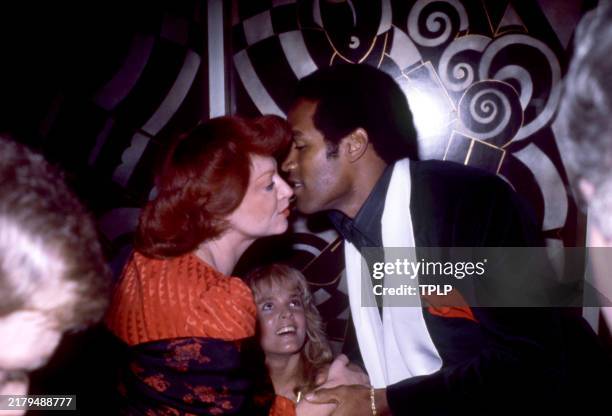 Former American football player O.J. Simpson kissing an unidentified woman as Simpon's girlfried and future wife Nicole Brown smiles at an...