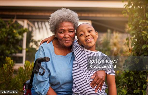 great grandmother sitting in seat walker hugging little great granddaughter, smiling together at camera in garden - great grandmother stock pictures, royalty-free photos & images