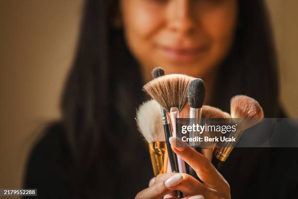 une jeune femme tient des pinceaux de maquillage. - pinceau à maquillage photos et images de collection