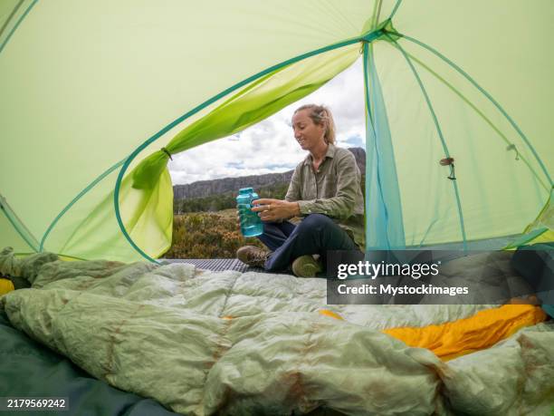 camper sitting inside tent with scenic mountain view - camping selvagem imagens e fotografias de stock