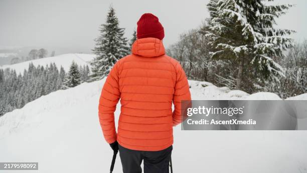 male hiker ascends slope in winter - puffer jacket stock pictures, royalty-free photos & images