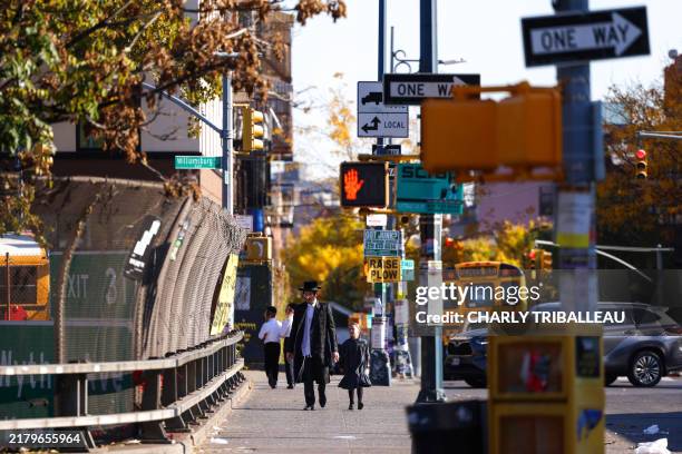 Ultra-Orthodox Jewish people walk in the Williamsburg neighborhood of the Brooklyn borough of New York City on October 21, 2024 during the holiday of...