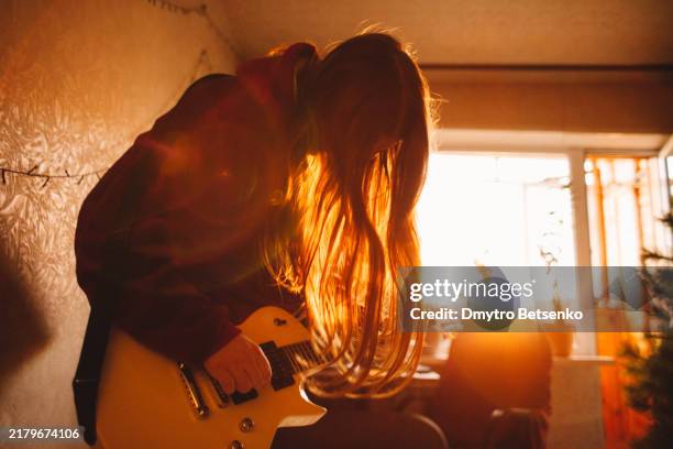 young woman playing electric guitar at home - plucking an instrument stock pictures, royalty-free photos & images