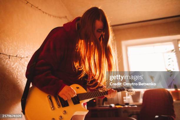 young woman playing electric guitar standing on the bed at home - rocking bed stock pictures, royalty-free photos & images