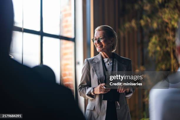 profesional sonriente hablando en una conferencia de negocios en una sala iluminada por el sol - asertividad fotografías e imágenes de stock