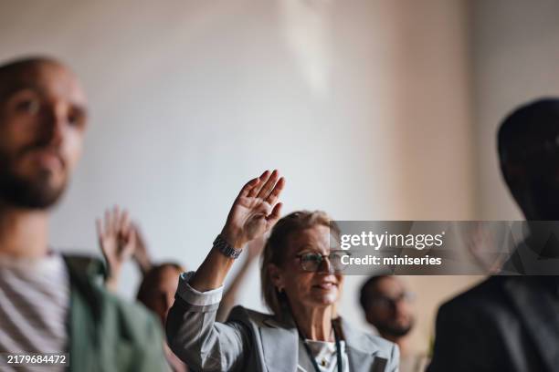 engaged audience at business conference raising hands - voorzitter stockfoto's en -beelden