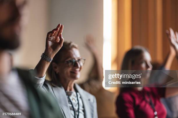 engaged participants raising hands during business conference session - congregation stock pictures, royalty-free photos & images
