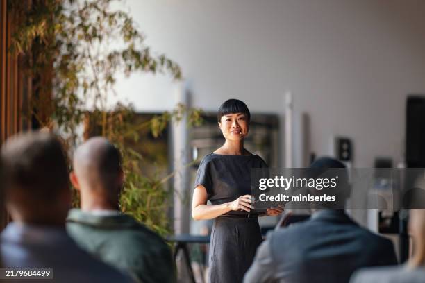 confident presenter leading business conference with engaged audience - leader stock pictures, royalty-free photos & images
