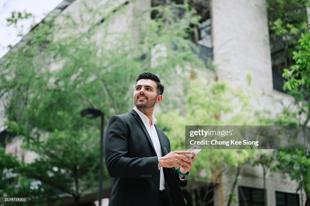 Low angle photo of Indian businessman with phone.