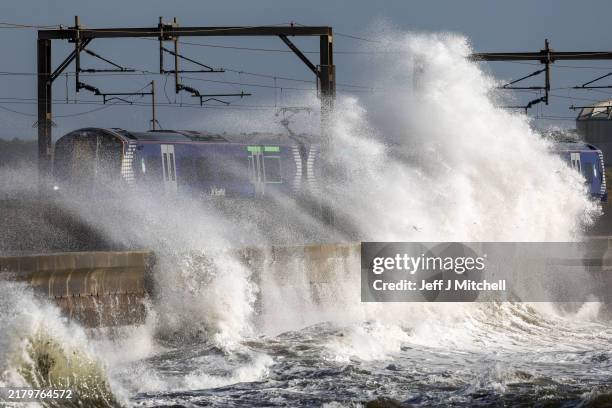 Train passes as waves crash against the sea defences as storm Ashley arrives on October 20, 2024 in Saltcoats, Scotland, United Kingdom. The Met...