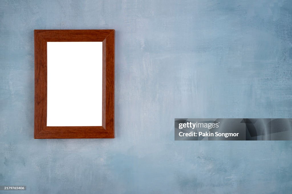 Blank Picture Frames Hanging on blue cement wall.