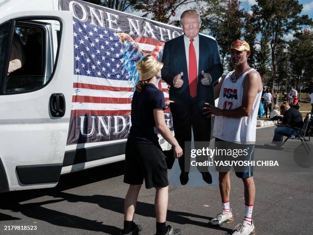 Garrett Vinson helps to carry a life-size portrait of former US President and Republican presidential candidate Donald Trump before a campaign rally...