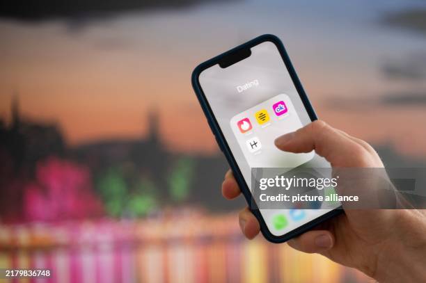 October 2024, Lower Saxony, Hanover: ILLUSTRATION - A woman holds a smartphone on which the dating apps Tinder, Bumble, OkCupid and Hinge are...